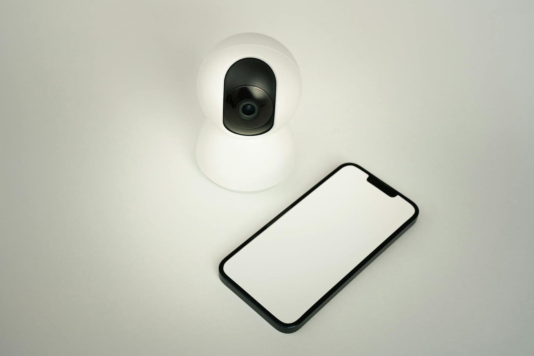 A smart home security camera paired with a blank smartphone on a white background. on Affordable Smart Living