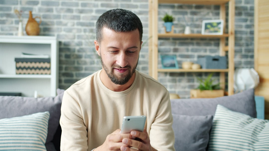 Man sitting on couch using a smartphone on Affordable Smart Living