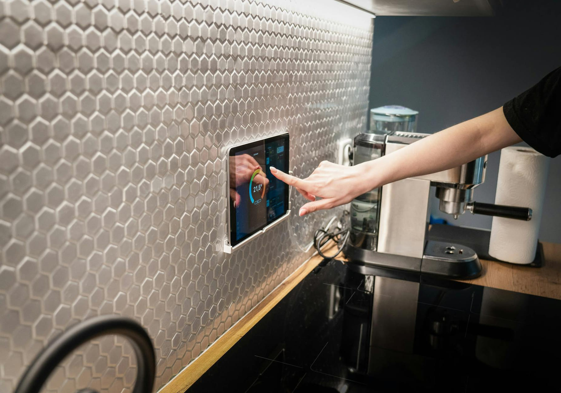 A modern kitchen with a touchscreen smart home control panel integrated into a hexagon-patterned wall. on Affordable Smart Living