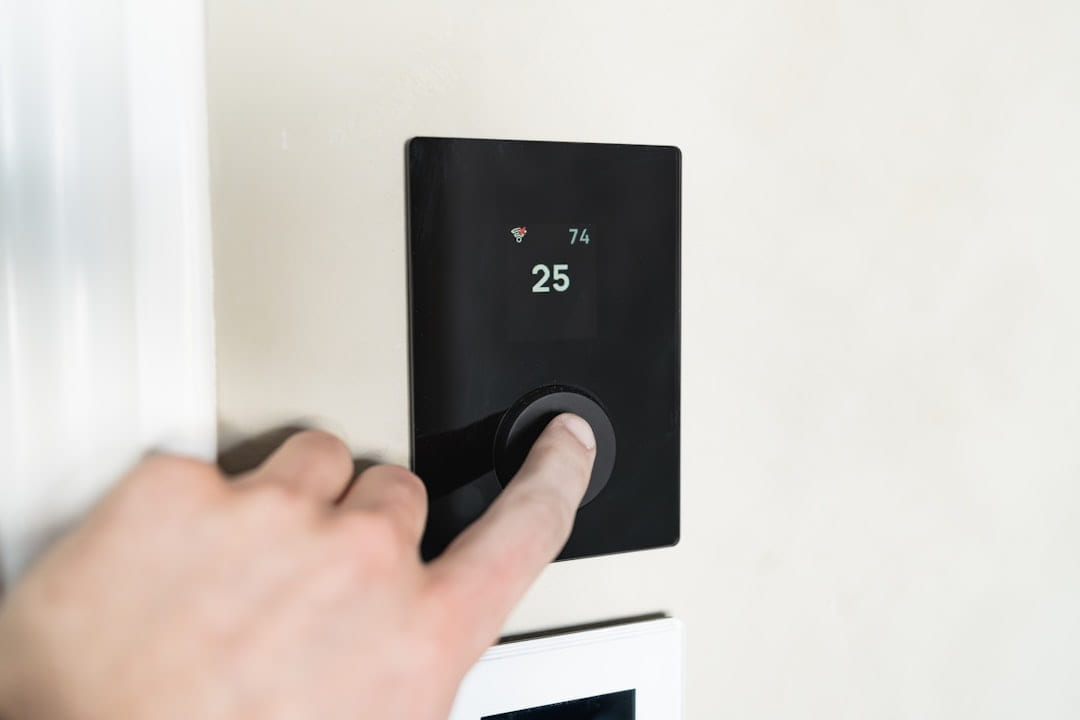 Finger pressing button on digital thermostat display. on Affordable Smart Living