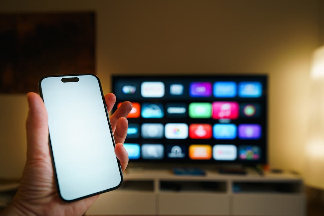 Smartphone held in front of a smart TV screen on Affordable Smart Living