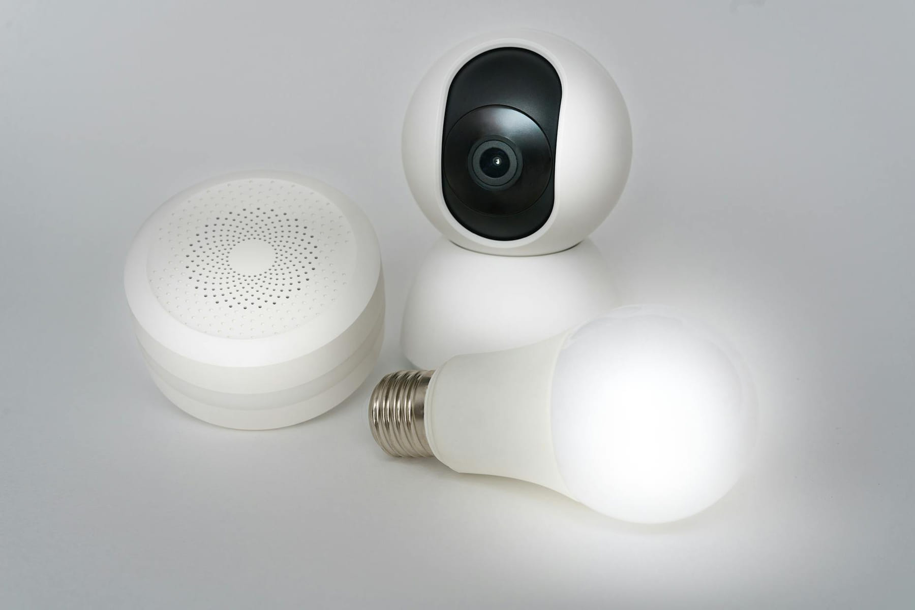 A set of smart home devices including a camera, speaker, and lightbulb on a white background. on Affordable Smart Living