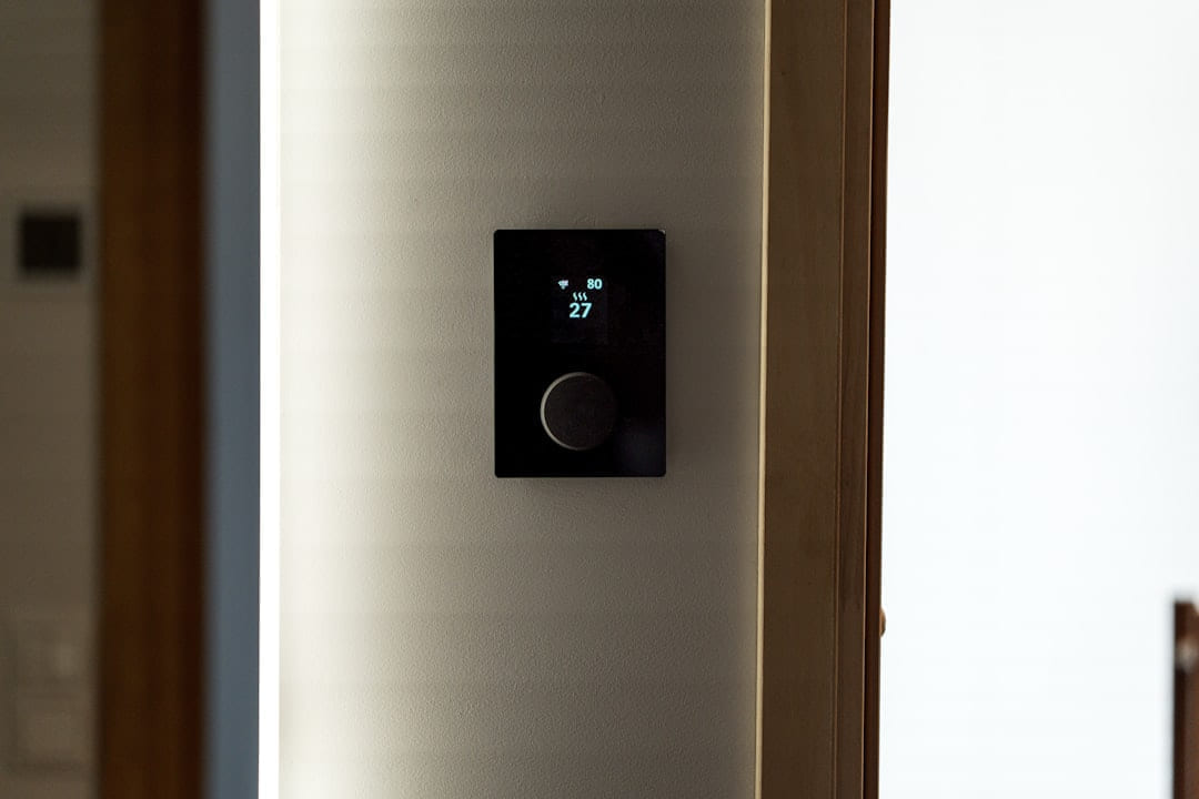 A modern black thermostat mounted on a wall. on Affordable Smart Living
